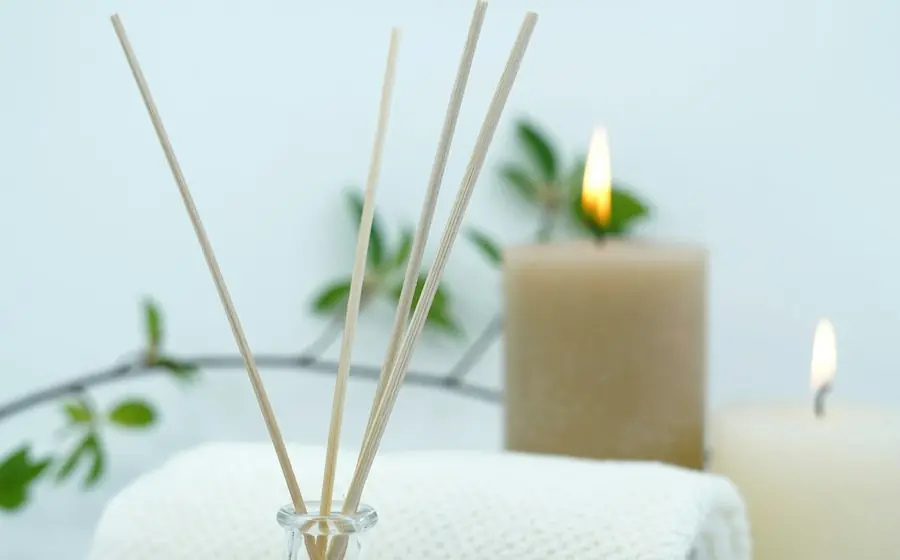 A spa scene with a candle, reed diffuser and a folded towel